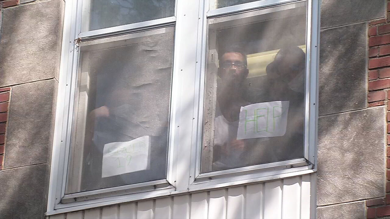 Residents of Dismass Charaties - St. Ann's halfway house hold up signs asking for help
